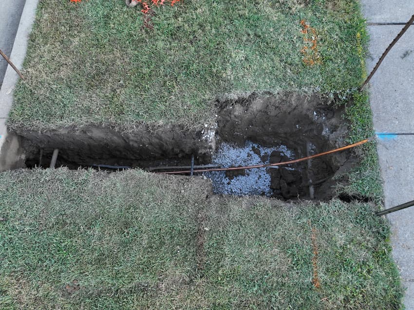 Hole in ground with lead pipe being replaced